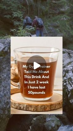 a cup of tea sitting on top of a wooden coaster in front of some rocks