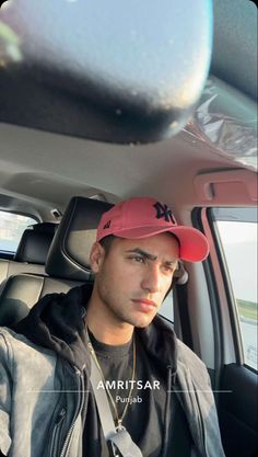 a man sitting in the back seat of a car wearing a red hat and jacket