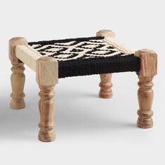 a small wooden stool with black and white rug on it's legs, sitting against a plain background