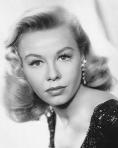 an old black and white photo of a woman with blonde hair wearing large earrings on her head