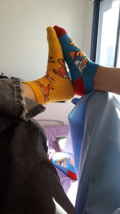 the person is wearing socks with cartoon characters on them and they are laying in bed