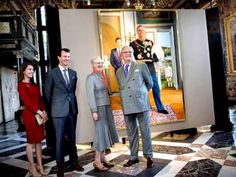 three men and two women standing in front of paintings