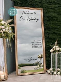 a large mirror sitting on top of a floor next to flowers and candles in front of a wall