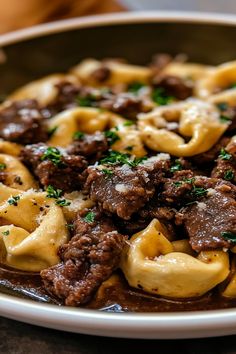 a plate full of pasta with beef and sauce on it, sitting on a table