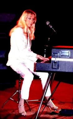 a woman sitting at a keyboard in front of a microphone