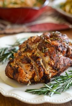 a piece of meat sitting on top of a white plate next to a green sprig