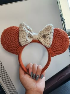 a person holding up a crocheted mickey mouse ears headband