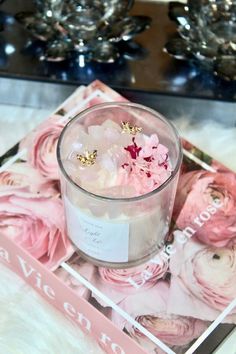 a candle with pink flowers in it sitting on a tray