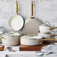 white pots and pans with gold handles on a table