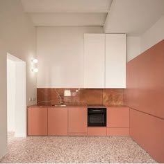 an empty kitchen with pink cabinets and marble counter tops