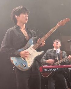 two young men are playing guitars on stage