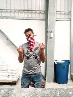 a man wearing a bandana standing in front of a pile of sandbags and looking at the camera