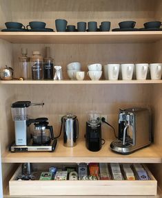 the shelves are filled with cups and coffee maker, mugs, and other kitchen items