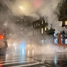 steam rises from the ground in front of a building on a city street at night