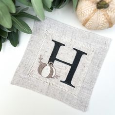 a close up of a cloth with the letter h on it next to some plants