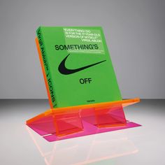 the book is sitting on top of an orange and pink stand with it's cover open