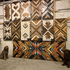 two dogs are sitting in front of some wood panels on the wall and another dog is looking at them