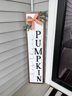 a wooden sign that says pumpkin hanging on the front door with a bow around it