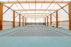 an indoor tennis court with white walls and blue flooring is seen in this image