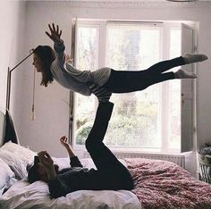 a man and woman jumping in the air on a bed with their hands up to each other