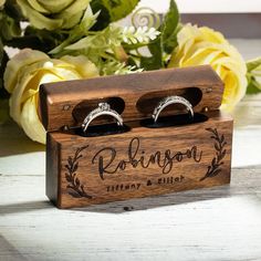 personalized wooden ring box with two wedding rings in it and yellow roses behind them