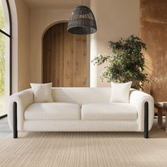 a white couch sitting next to a wooden table in a living room on top of a rug