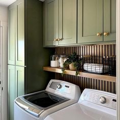 a washer and dryer in a room with green cupboards on the wall