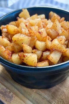 cinnamon apples in a blue bowl on a wooden table with text overlay that reads, cinnamon apples