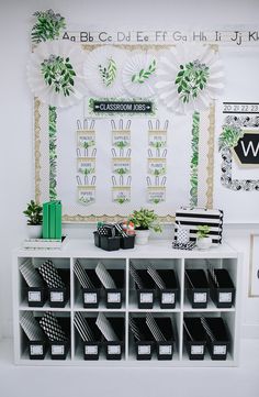 a white table topped with lots of black and white boxes next to a shelf filled with books