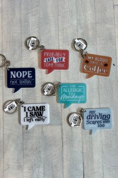 six keychains with different sayings on them sitting on a wooden table together