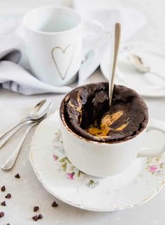 a white cup filled with chocolate cake on top of a saucer