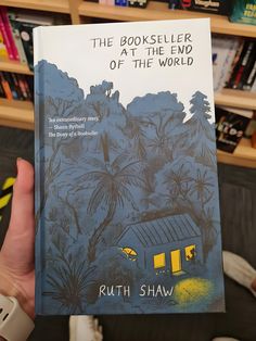 the book seller at the end of the world by ruth shaw is held up in front of a bookshelf