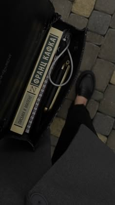 a person is holding an electronic device in their hand while standing next to a brick walkway