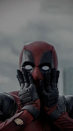 a man in a deadpool costume holding his hands up to his face and looking at the camera