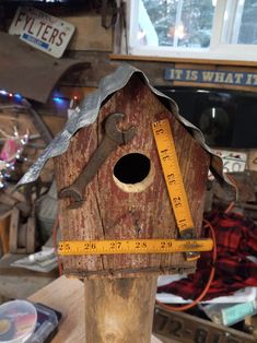 a wooden birdhouse with a measuring tape around it's neck and the roof