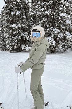 a person on skis standing in the snow with trees behind them and wearing goggles