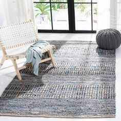 a white chair sitting on top of a rug in front of a window next to a wooden bench