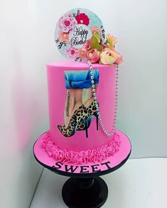 a pink birthday cake with high heel shoes and flowers on the top is decorated with an image of a woman's shoe