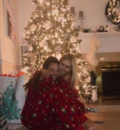 two women hugging each other in front of a christmas tree