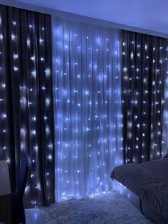 a bed room with a neatly made bed and lights on the wall behind it's sheer curtains