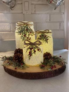 a lighted cake decorated with pine cones, berries and evergreens on a wood slice