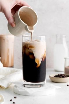 someone pouring coffee into a tall glass with ice cream and chocolate chips on the side