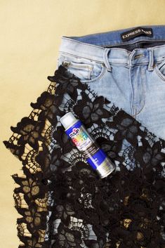 a pair of jeans with lace on them and a can of spray paint sitting next to it