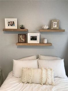 a bed with white linens and two wooden shelves above it