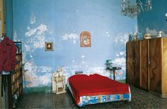 a bedroom with blue walls and a red bedspread on the bed in it