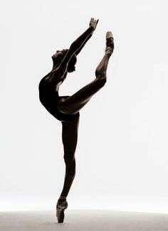 a woman in black leotard and ballet shoes doing a handstand pose