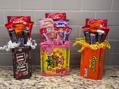 three candy boxes with different flavors in them on a counter top next to a tile wall