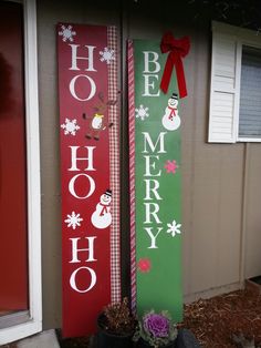 two wooden christmas signs sitting next to each other in front of a house with snowmen on them