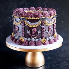 a purple and gold decorated cake sitting on top of a table