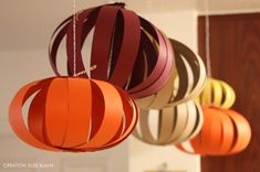 three paper lanterns hanging from the ceiling in different shades of orange, red and brown